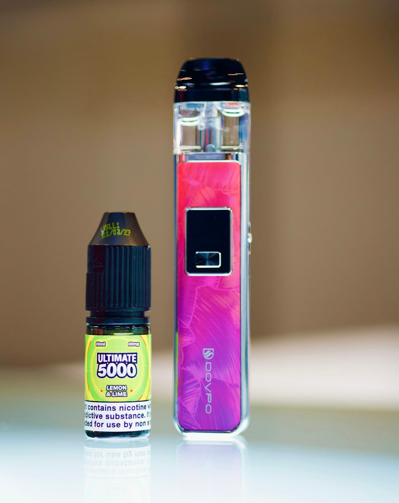 A 10ml nicotine salt e-liquid bottle carrying a printed nicotine warning label, standing next to a pod vape device