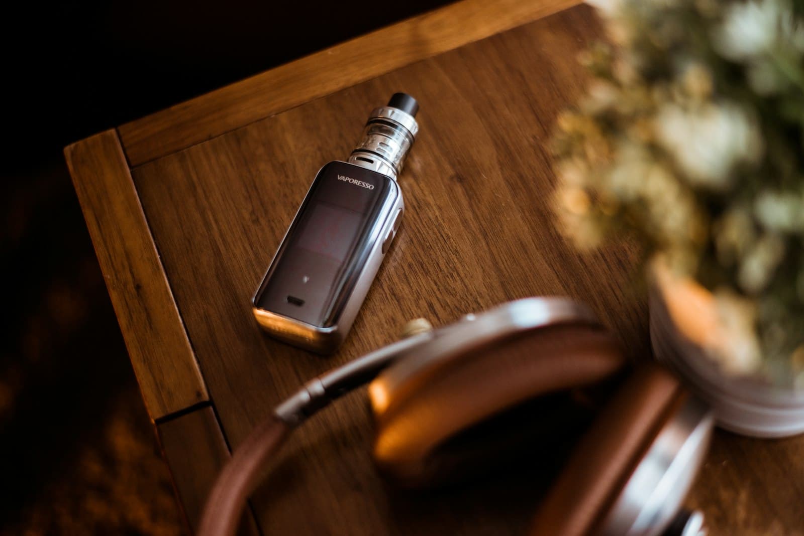 A black rechargeable pod mod device resting on a wooden surface